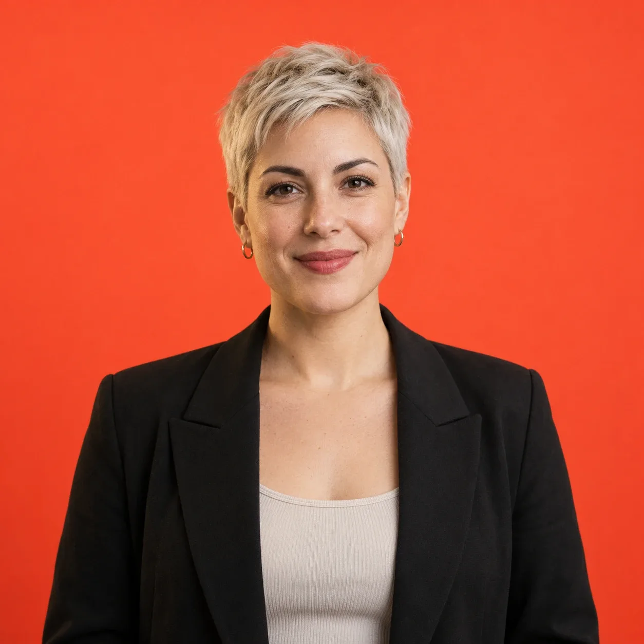 Woman in her 30s with cropped platinum hair and a black blazer, chest-up