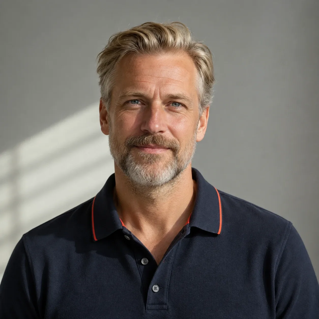 Tall Scandinavian man in his late 40s with swept-back blond-grey hair and a trimmed beard