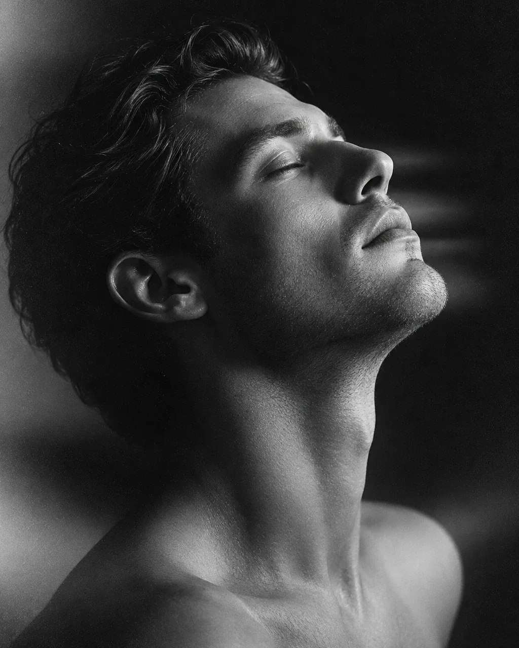 Black-and-white studio portrait of a person in profile with head tilted back