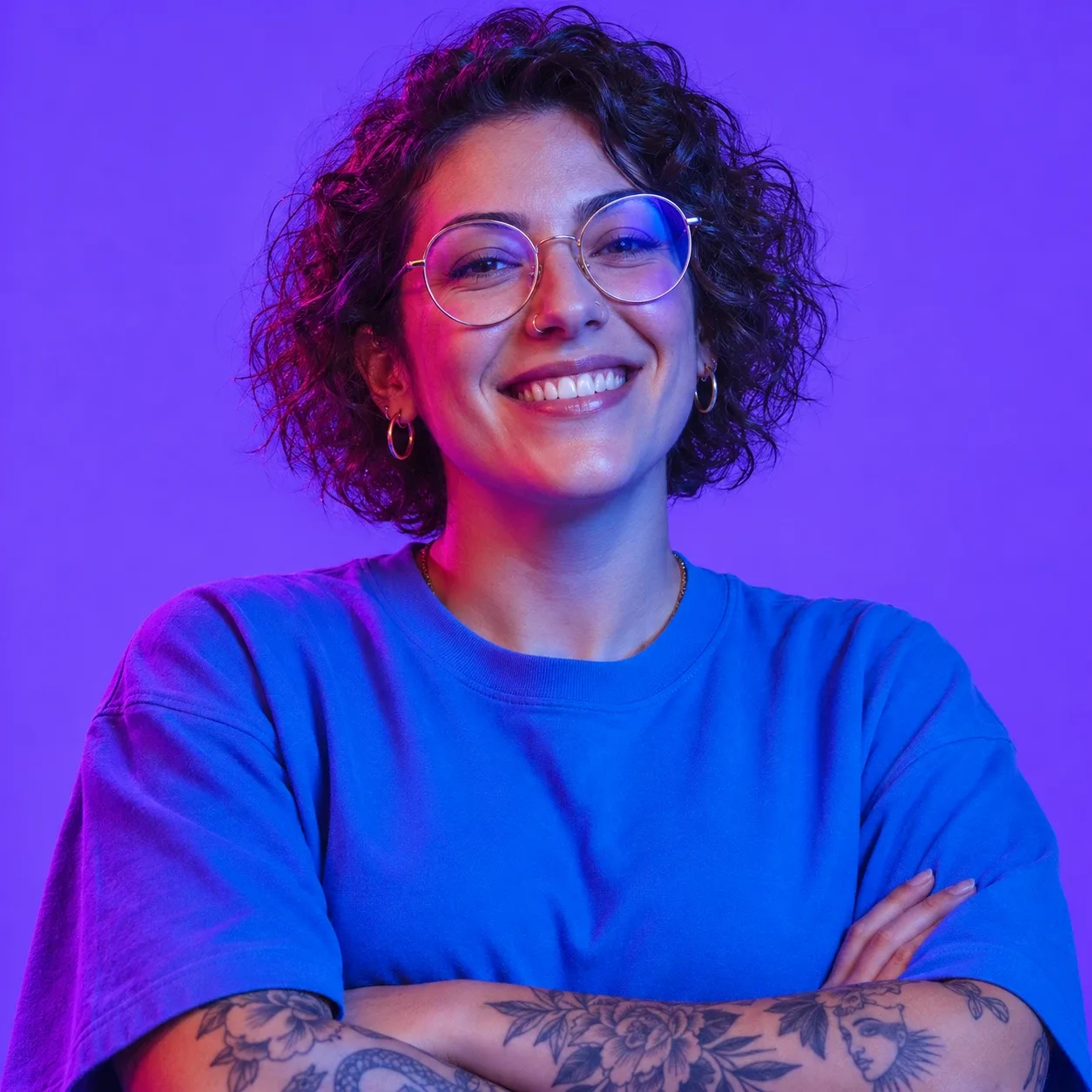 A smiling woman with short curly hair and round glasses