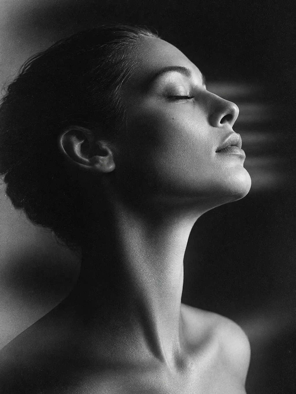 Black-and-white studio portrait of a person in profile with head tilted back