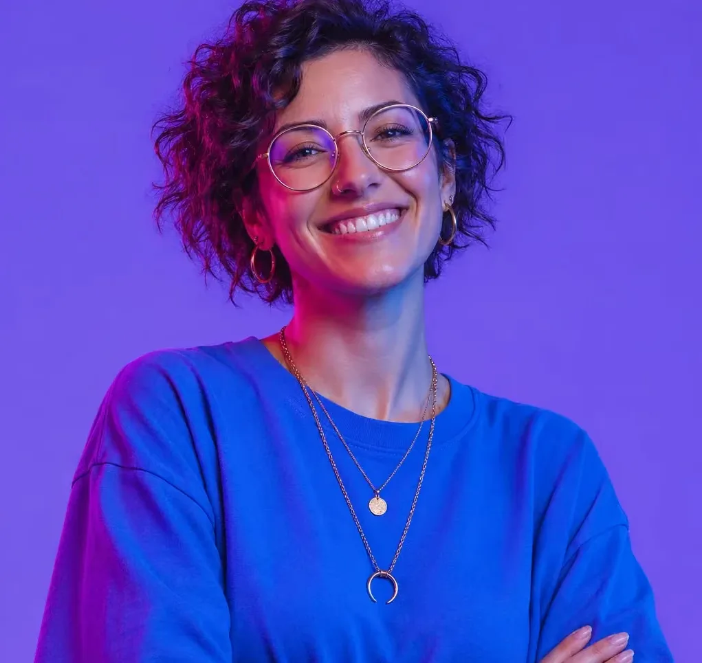 A smiling woman with short curly hair and round glasses