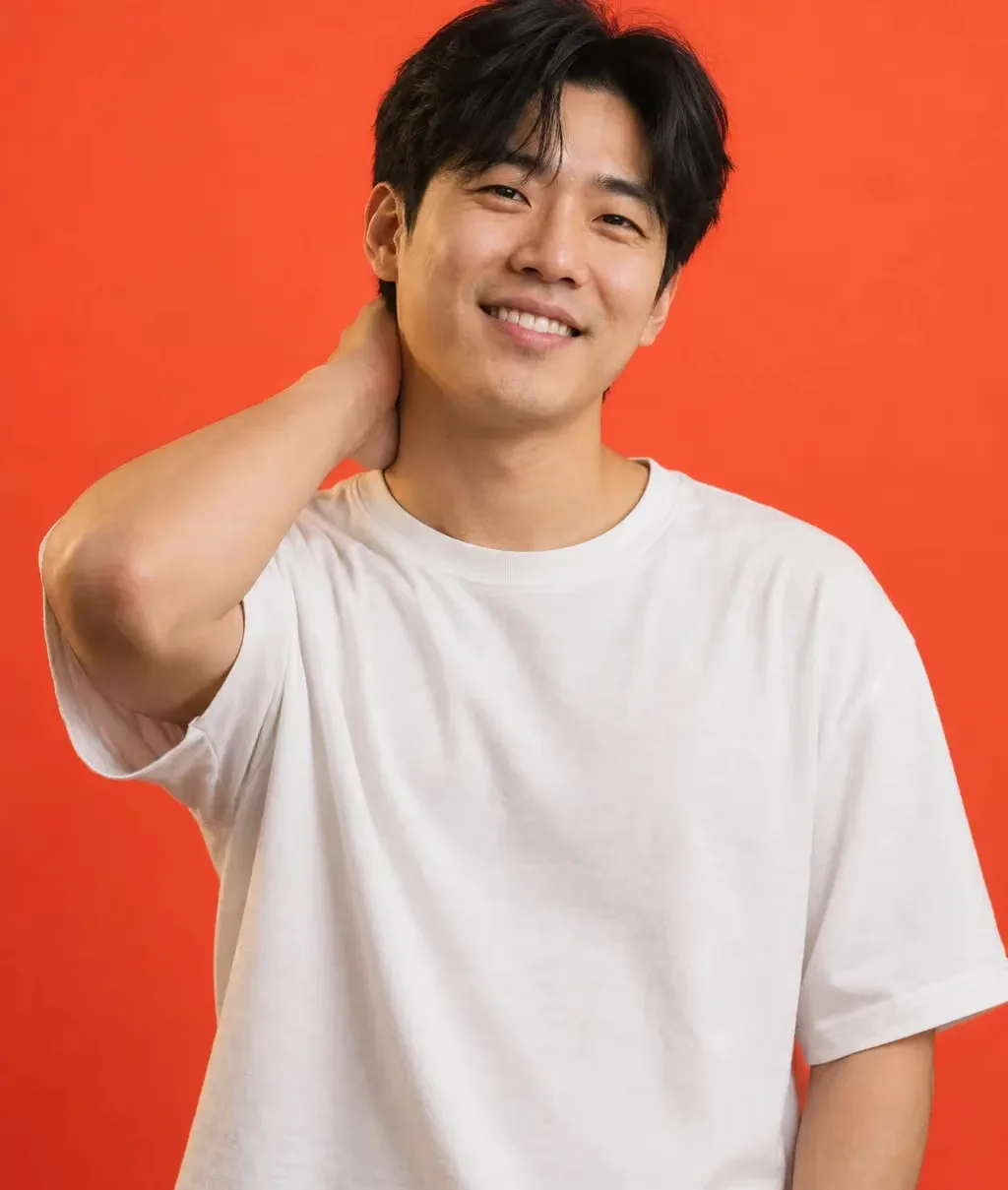 Man in his early 30s with black hair falling over his forehead and an oversized plain white tee