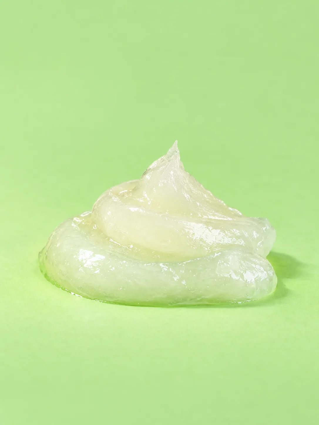 Glossy translucent balm texture on a luminous spring-green surface.
